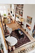 Blick auf offenes Wohnzimmer mit Bücherregalen, Kamin und marokkanischem Teppich