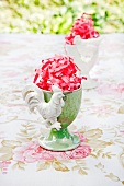 Outside -- egg cups filled with pink Easter grass on a rose patterned tablecloth