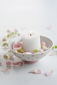 Candle in a little bowl surrounded by petals