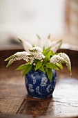 White profusion (Buddleia davidii) in a small blue vase