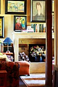 Collection of paintings in living room of old country house - modern paintings above open fireplace on wall painted yellow