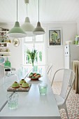 Pendant lamps in various shades of green above freshly baked cakes on white dining table