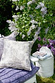 Lilac cushions on garden chair next to flowering lilac