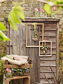 Old wooden shed decorated with vintage picture frames and flowers in front of brick wall