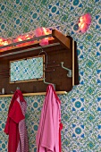 Fairy lights on vintage coat rack on wall with patterned wallpaper