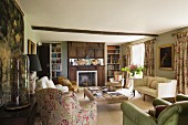 Klassisch englischer Wohnraum mit holzvertäfeltem Kamin und verschiedenen Sesseln um grossen Polstertisch