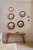 Rustic bench and round, framed convex mirrors on wall