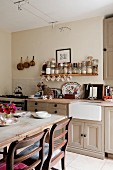 Dining area in front of kitchen counter below open spice shelf in English country-house kitchen