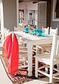 Red towel on a white, lacquered wooden chair and table on a terrace