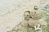 Man and woman figures made of sand on beach
