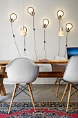 Bauhaus shell chairs at rustic wooden table in front of modern scone lamps