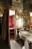 Sconce lamps and pedestal sink in ensuite bathroom with mirrored ceiling and walls