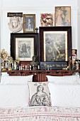 Sammlung von Heiligenbildern und -figuren am Kopfende eines Bettes; mit Madonnenbild und Herzen bedrucktes Dekokissen