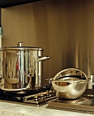 Stainless steel pan on hob and chrome mixing bowls