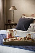 Tea set with toile de jouy pattern on tray on double bed