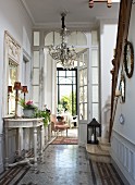 Elegant hallway with Baroque console table, chandelier and staircase with stone treads and wooden balustrade