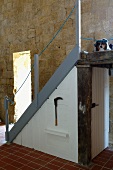 Australian Shepherd on landing of staircase with integrated cupboard in front of sandstone wall (Chateau Maignaut)