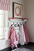 Dish towels hanging on white, lacquer coat rack next to a window in a kitchen corner