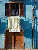 Pastellblaue Hausfassade eines sardischen Hauses mit trocknender Wäsche