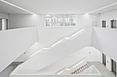 weiße Treppenläufe um grosszügigem Treppenauge in moderner Architektur