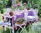 A table laid outside decorated with flowering artichokes and a purple cloth
