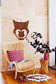 Rattan chair in front of light wooden panel with owl decoration
