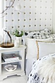Many scatter cushions on bed with upholstered headboard and bedside cabinet in Scandinavian country-house style