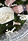 Woman's hands threading popcorn for Christmas tree garlands