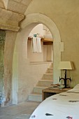 View from a rustic bedroom of an archway and stone stairway to the en suite bathroom