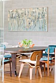 Bauhaus wooden chairs around dining table and modern artwork on pale grey stone wall