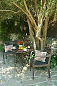 Vintage garden chair and table in front of tree on stone-flagged terrace