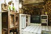 Alte Kücheneinrichtung mit modernem Herd auf gefliestem Podest im Rustiko
