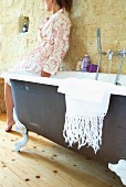 Frau sitzt auf Badewannenrand im Bad des Château Maignaut (Pyrenäen, Frankreich)