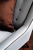 Detail of silver grey armchair with copper-coloured cushion