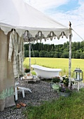 Bathtub on gravel in front of Oriental-style tent and view of landscape