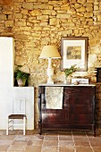 Antique chest of drawers against rustic stone wall in Mediterranean interior