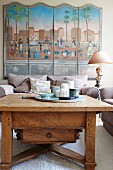 Rustic coffee table and upholstered armchairs in front of multi-panelled picture