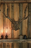 Stag's head and antlers made of twigs and pine-cone candlesticks on wooden beam