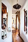Curved hallway with tree trunks as ceiling props and ethnic artworks on walls