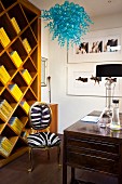 Yellow books in original shelving unit; pretty, blue glass lamp in foreground above Baroque chair with zebra skin upholstery