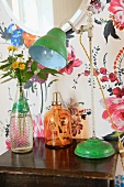 Lamp and bottles on bedside table against floral wallpaper