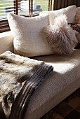 Light couch with cozy, fur look pillows and throw