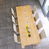 Top view of wooden dining table and chairs with pale covers on light grey stone floor in minimalist setting