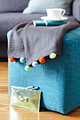 Grey blanket decorated with colourful pompoms
