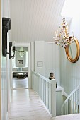 White-painted landing with gilt-framed mirror and chandelier
