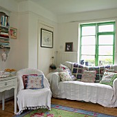 Country-house living room with white and patchwork blankets and patchwork and floral cushions on armchair and sofa