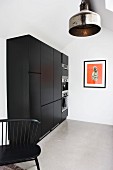 Black kitchen cabinet with fitted appliances and industrial-style, metal pendant lamps