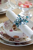 Festive place setting with floral crockery and linen napkin in beaded napkin ring