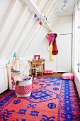 White painted wood panelling and red and blue kilim rug in girl's bedroom with sloping ceiling
