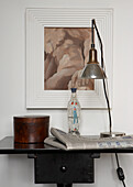 Desk lamp next to vintage bottle on black console table